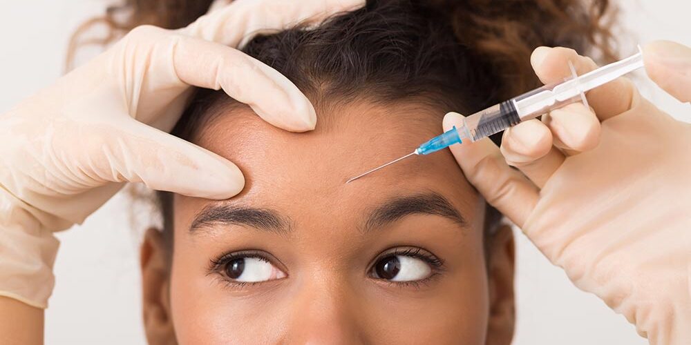 African american woman getting botox injection in forehead