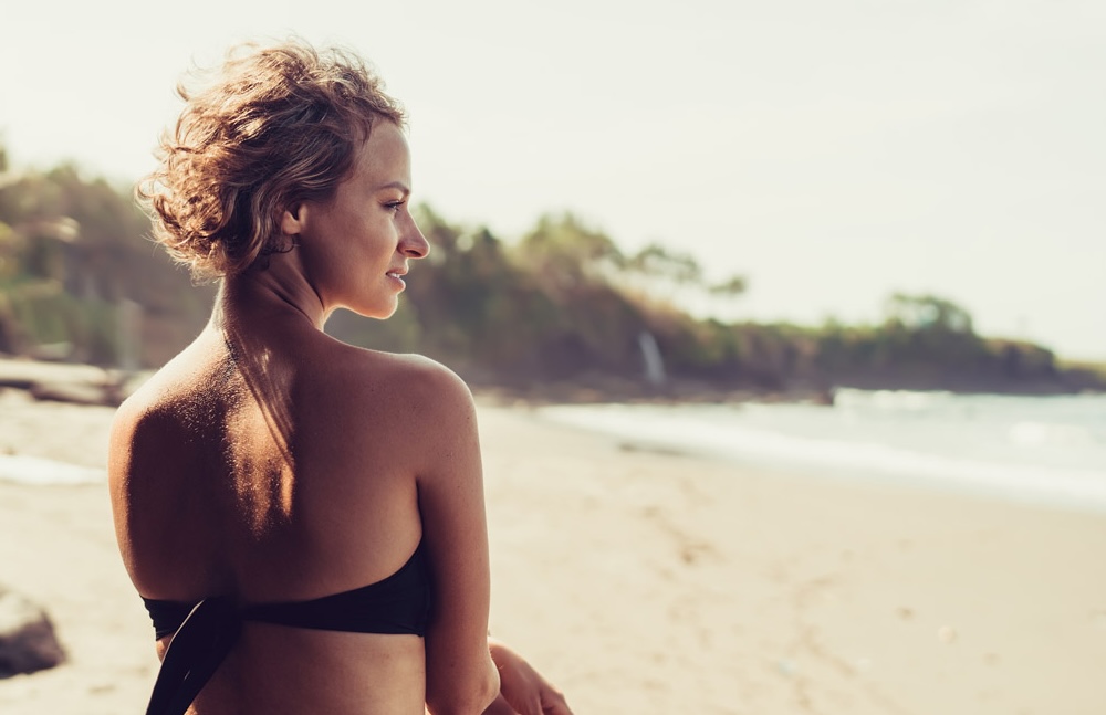 A woman on the beach, watching the waves crash