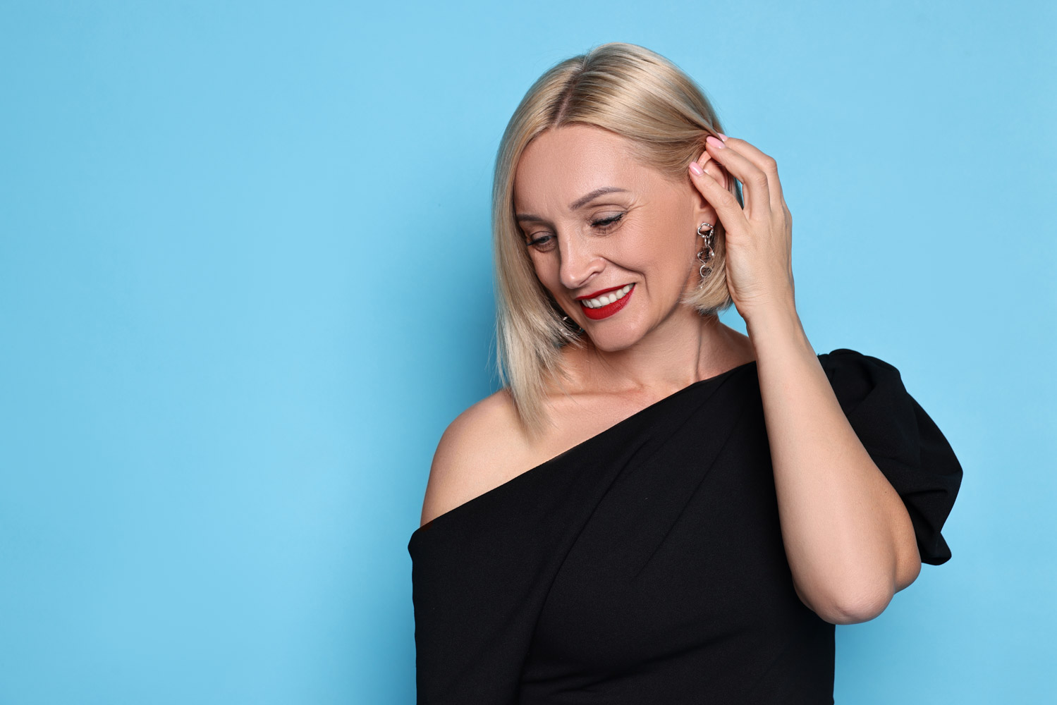 An elegant woman pushes the hair back from her ears