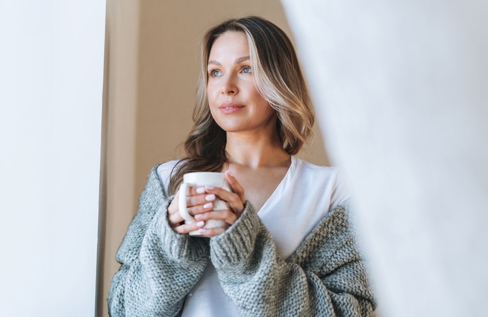 A woman sips coffee, hapy with her Ulthera treatment